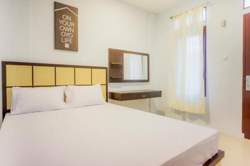 a bedroom with a white bed and a mirror at OYO Life 2354 Rose House in Medan