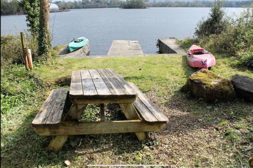 a wooden picnic table next to a lake with two boats at Bluebell lake house in Enniskillen