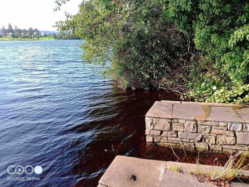 a stone wall next to a body of water at Bluebell lake house in Enniskillen