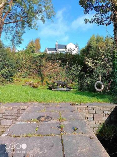 a picnic table in the grass with a house in the background at Bluebell lake house in Enniskillen