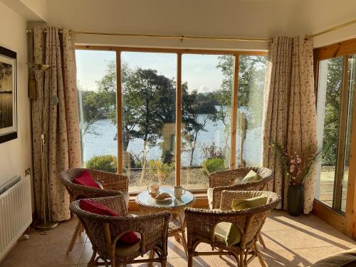 a living room with a table and chairs and a large window at Bluebell lake house in Enniskillen