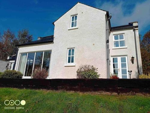 a large white house with large windows at Bluebell lake house in Enniskillen