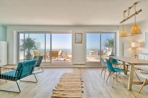 - un salon avec une table et des chaises et une vue sur l'océan dans l'établissement Vue sur mer La Baule Moana, à La Baule