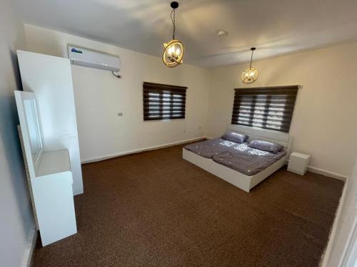 a bedroom with a bed and two windows at Wadi Al-Nakhil Hostel in Al Khuraybah