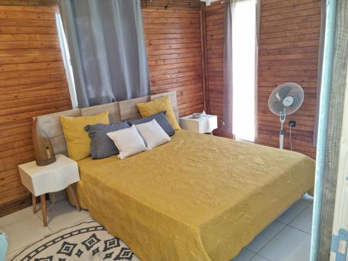 een slaapkamer met een bed met gele en blauwe kussens bij Le chal'heureux in Chirongui