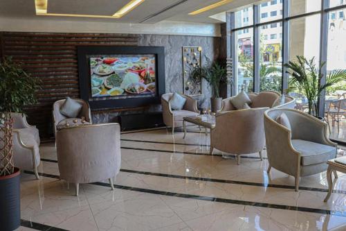 a lobby with chairs and a television in a building at Rival Hotel Amman in Amman