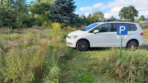 a white car parked in a field with a parking sign at FeWo "Falter" im Kunstgut Krahne in Krahne