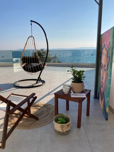 a patio with a swing and a bench and a table at Wide Blue Luxury Boutique Suites in Neos Marmaras