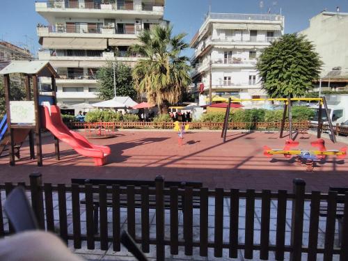 plac zabaw z czerwoną zjeżdżalnią i huśtawkami w obiekcie Katrin's House w Salonikach