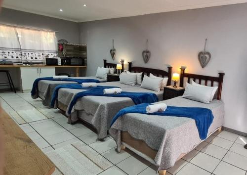 a room with four beds with blue blankets on them at Tehillah Guesthouse in Upington