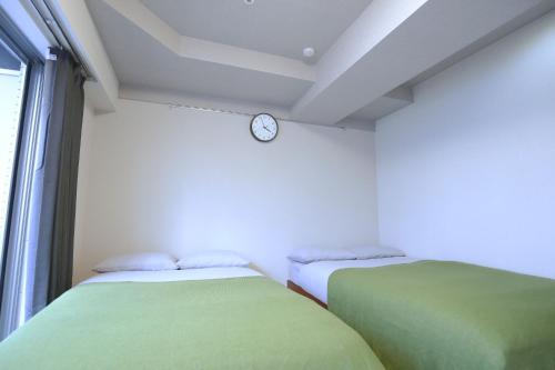 two beds in a room with a clock on the wall at Shinjuku Ryokan Retreat丶Local Tokyo Experience & Short Trips Hub丶walk to Higahsi Shinjuku station YEoL in Tokyo