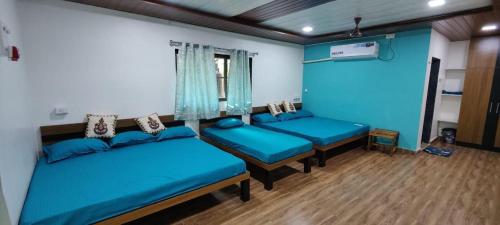 una habitación con tres camas azules. en NS Brothers Farm & Resort, en Kolād