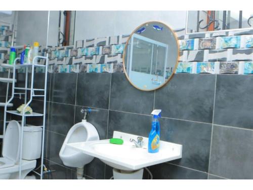 a bathroom with a mirror and a sink and toilets at Alice Gardens & Campsite in Entebbe