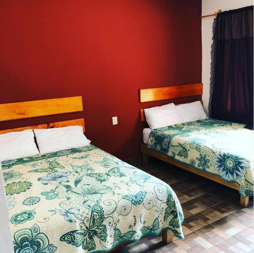 1 dormitorio con 2 camas y pared roja en Hotel Pedregal, en Tamasopo