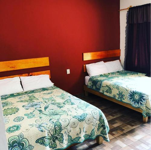 - une chambre avec 2 lits et un mur rouge dans l'établissement Hotel Pedregal, à Tamasopo