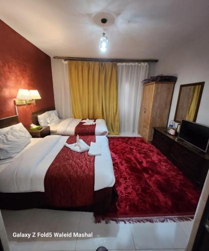 um quarto de hotel com duas camas e um tapete vermelho em Rabail House em Wadi Musa