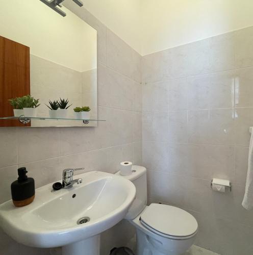 a white bathroom with a toilet and a sink at Beach Relax Apartment in Porto Santo