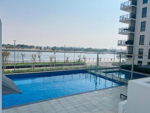 a large swimming pool with a view of a river at Yas Island 1BR Apt with balcony near Sea World in Abu Dhabi