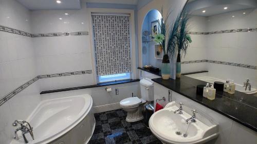 a bathroom with a tub and a sink and a toilet at Gorgeous 4-Bed House in Bexhill-on-Sea sea views in Bexhill