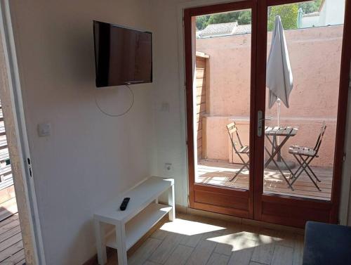 a living room with a tv and a sliding glass door at studette a la moutonne in La Crau