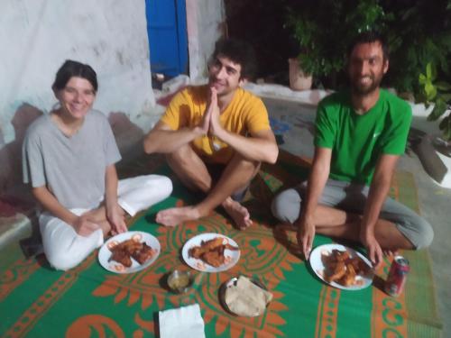 three people sitting on the floor with plates of food at Orchha Best Homestay in Orchha