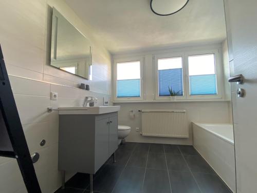 La salle de bains est pourvue d'un lavabo, d'une baignoire et de toilettes. dans l'établissement Ferienwohnung am Holzberg in Volkach mit Weitblick, à Volkach