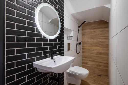 a bathroom with a white sink and a brick wall at 4 Pory Roku Apartamenty Domki Pokoje in Nadole