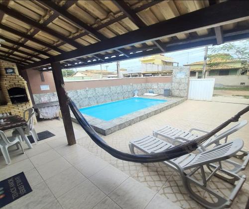 a hammock on a patio with a swimming pool at Meu lugar de Descanso in Cabo Frio