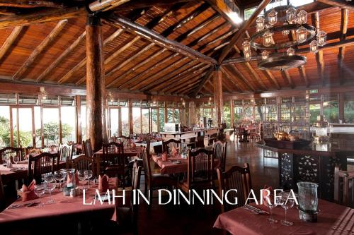 ein Restaurant mit Tischen und Stühlen in einem Zimmer in der Unterkunft Lake Manyara Wildlife Lodge in Mto wa Mbu