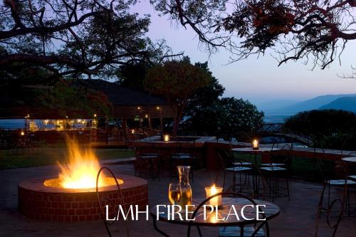 a fire place with tables and chairs at night at Lake Manyara Wildlife Lodge in Mto wa Mbu