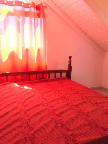 a bedroom with a red bed with a window at Appartements Bois Jolis in Rabi