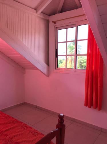 a bedroom with a red bed and a window at Appartements Bois Jolis in Rabi