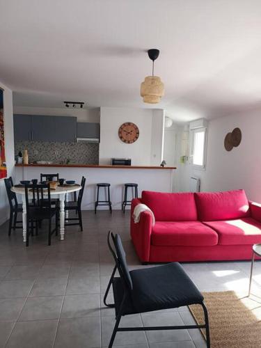 un salon avec un canapé rouge et une cuisine dans l'établissement La CASA INCA Mérignac - Appartement 3 pièces avec parking à proximité du Tram, à Mérignac