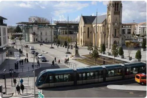 a train on a city street with a building at La CASA INCA Mérignac - Appartement 3 pièces avec parking à proximité du Tram in Mérignac