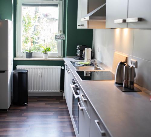 cocina con armarios blancos, fregadero y ventana en Zentral Smart Apartment, en Zwickau