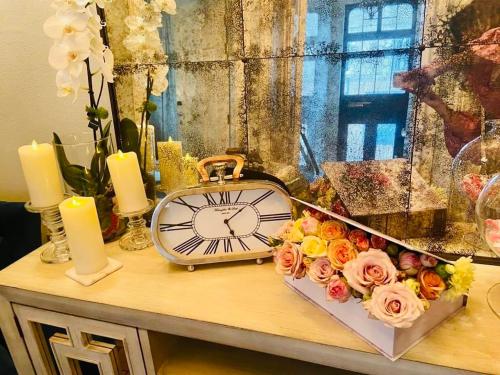 a clock sitting on a table with flowers and candles at 29A Guesthouse in Plovdiv