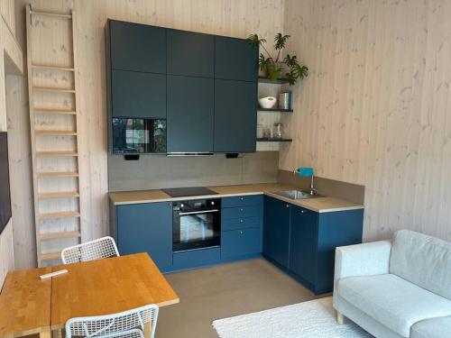 a kitchen with blue cabinets and a table and a couch at Mysigt attefallshus med närhet till stad och hav in Västra Frölunda