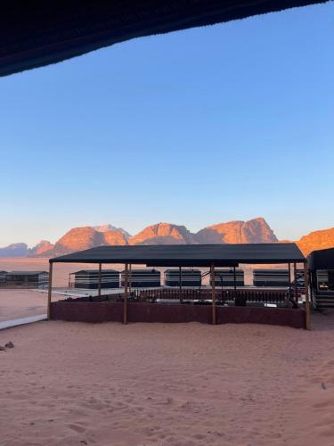 a pavilion on the beach with mountains in the background at Wadi Rum Star Camp in Wadi Rum
