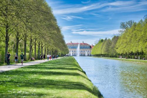 people walking along the canal in front of a building at Hotel am Schlosspark Zum Kurfürst in Oberschleißheim