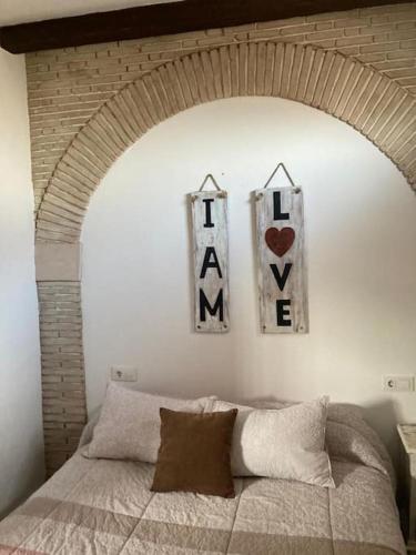 1 dormitorio con 1 cama con 2 letreros en la pared en Casa Puerta sierra de Cádiz, en Arcos de la Frontera