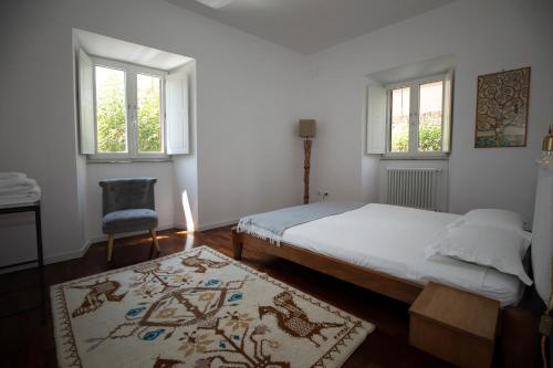 a bedroom with a bed and a chair and windows at Domus Cordara - Splendido appartamento nel verde in Rome