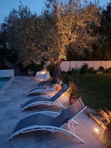 a row of benches sitting next to a tree at Maison de Charme - Maréchalerie - Nîmes in Uchaud