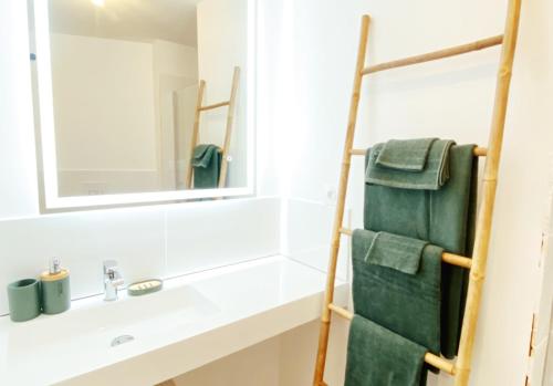 a bathroom with a sink and a mirror and green towels at Le TerraCotta ⸱ Stationnement gratuit ⸱ Fibre in Déols
