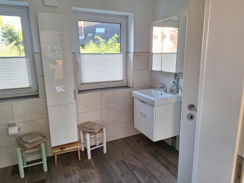 a small bathroom with a sink and two windows at Haus Swanhild in Fockbek