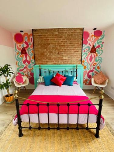 a bedroom with a bed with pink and blue pillows at Colourful Apartment in Margate in Kent