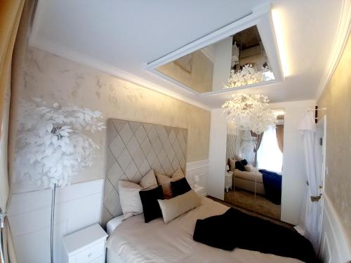 a bedroom with a white bed with a large headboard at Apartament Glamour Okrzei in Sandomierz