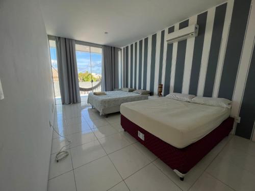 a bedroom with two beds and a large window at Casa de praia no Hibiscus Beach Clube, Condomínio Angras de Ipioca. in Maceió