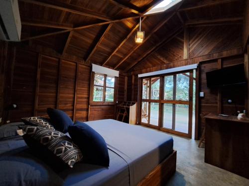 a bedroom with a bed with blue pillows and a television at Cabañas La Tortuga in Ayampe