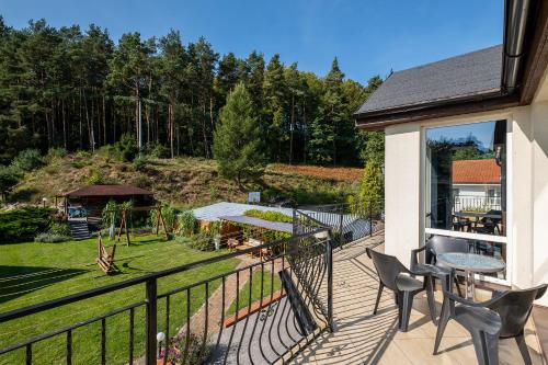 a balcony with a table and chairs and a garden at 4 Pory Roku Apartamenty Domki Pokoje in Nadole