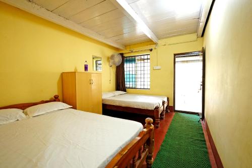 a room with two beds and a green rug at Karadikallu Homestay - Private Waterfalls & Guided Trek in Sakleshpur